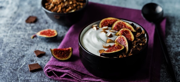 Greek yogurt chocolate almond nuts oatmeal granola with figs in a bowl.