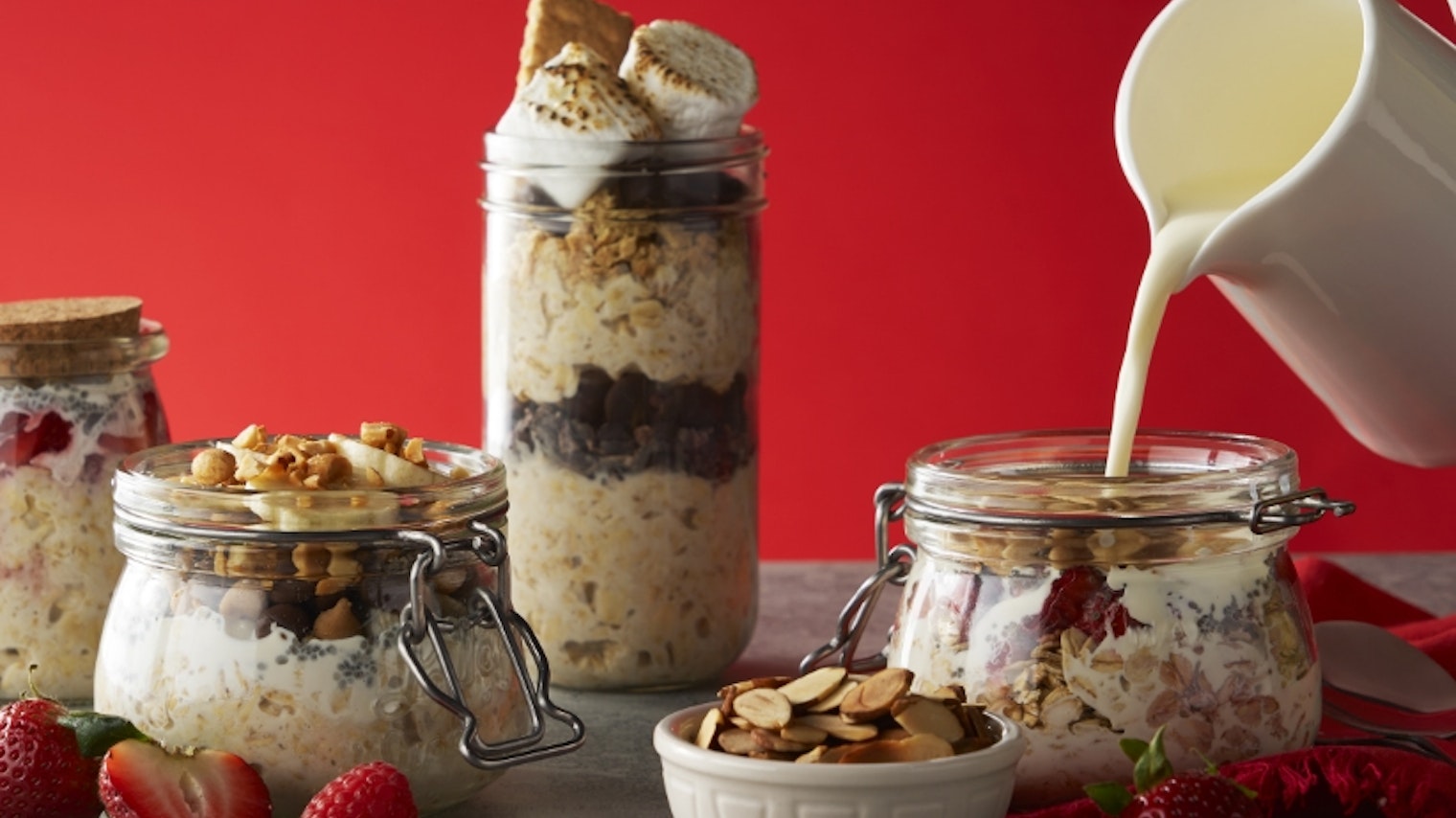 Mix of gourmet oatmeals with milk being poured in front of a red background