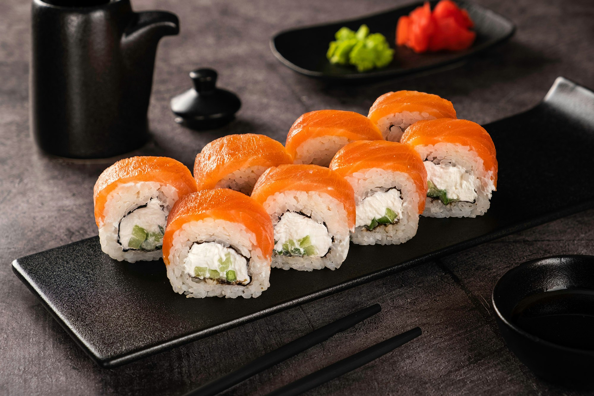 Fresh salmon sushi roll with cream cheese on black plate